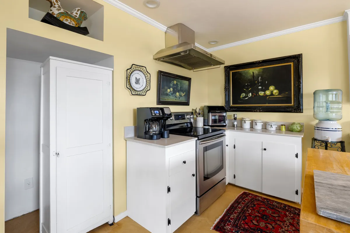 A modern kitchen equipped with stainless steel appliances, a coffee maker, and detailed artwork, accentuated by a warm, welcoming mood. The kitchen provides ample counter space for meal preparation, ideal for home-cooked breakfasts or dinners.