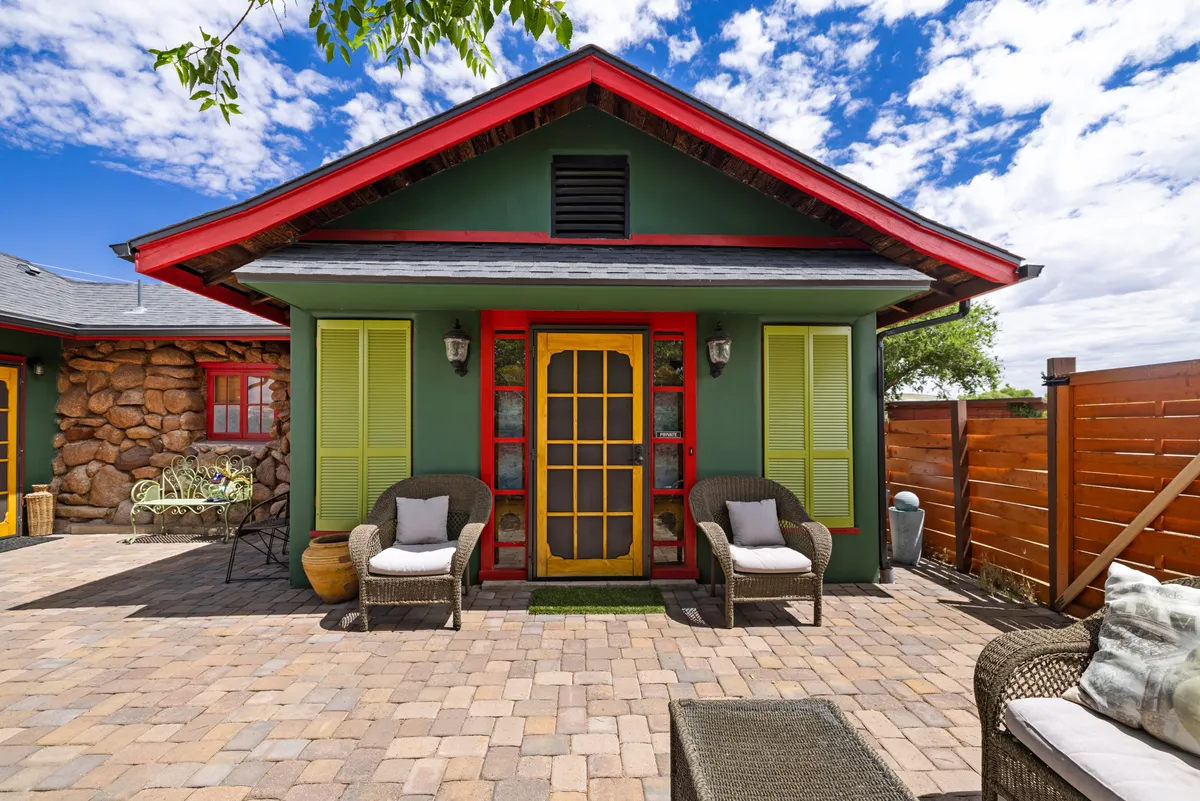 Cheerful patio scene with a vibrant yellow door, green walls, red accents, and comfortable seating. The space encourages relaxation and socializing, hinting at time spent planning or sharing stories from day trips.