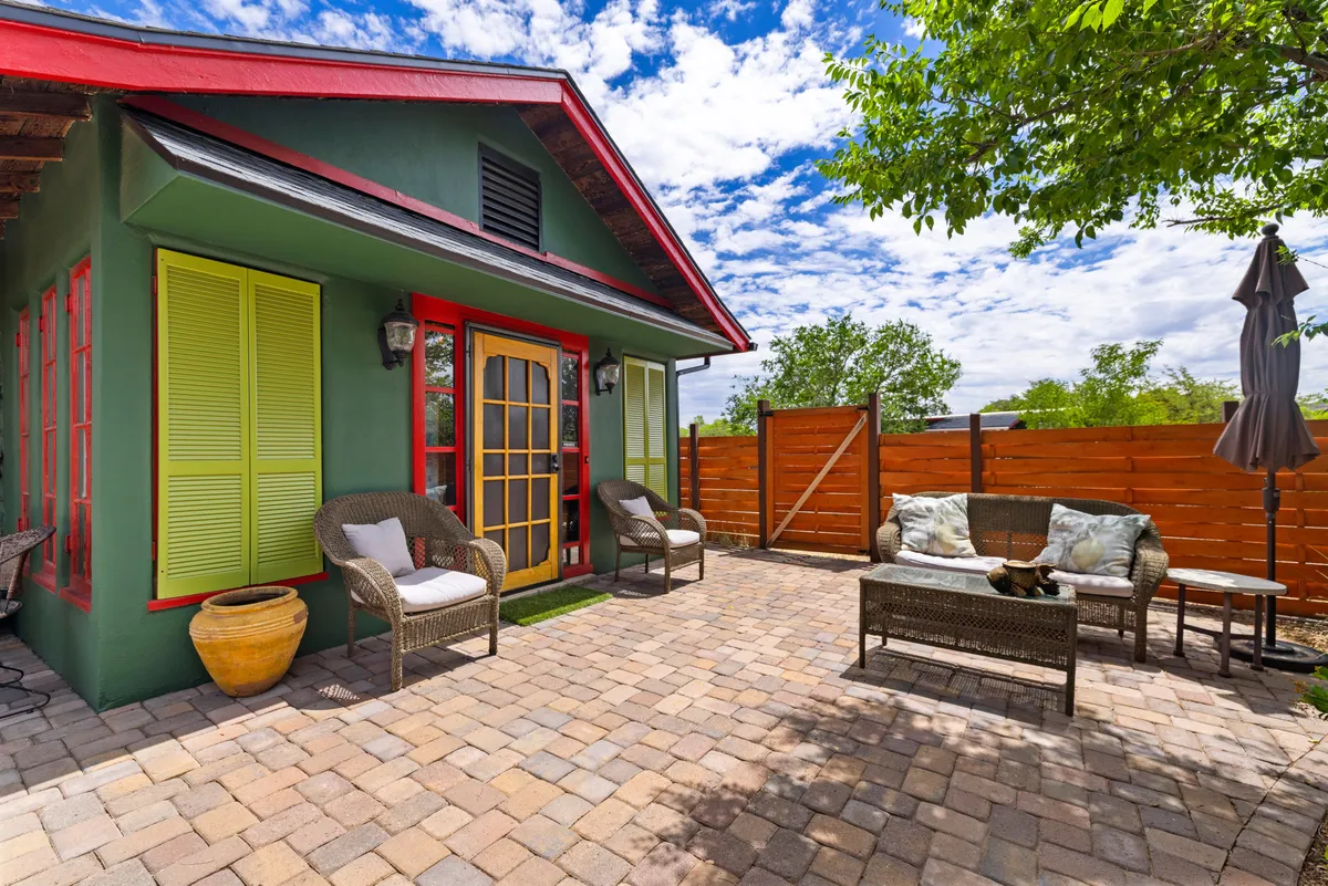 This image highlights a cheerful patio seating area set against a colorful house facade, with garden elements and lush greenery surrounding the space. The seating arrangement invites relaxation, socializing, or enjoying a meal, and the overall atmosphere feels open and connected to the outdoors.